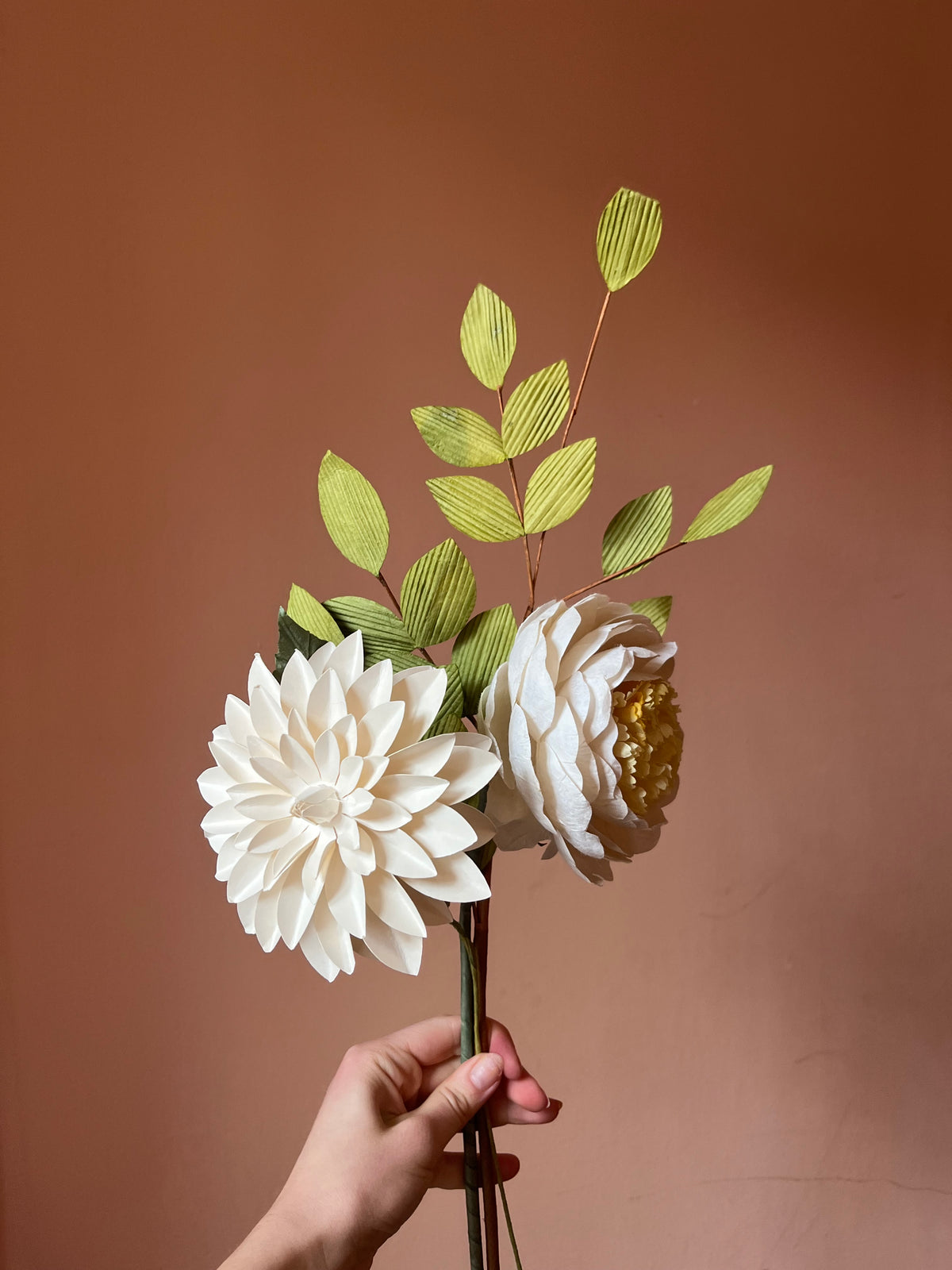 Hånd holder creme evighedsbuket af papirblomster med dahlia og rose