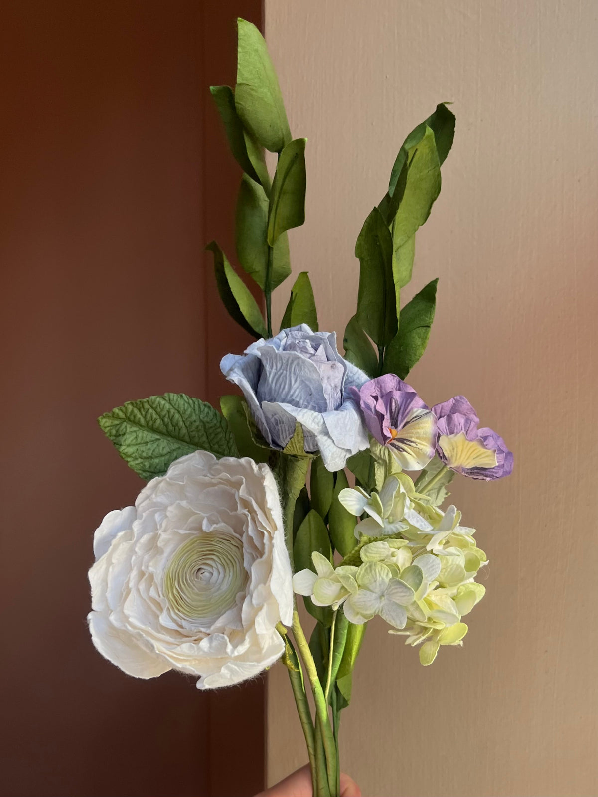 Nærbillede af hvid ranunkel, blå rose og hortensia i papir
