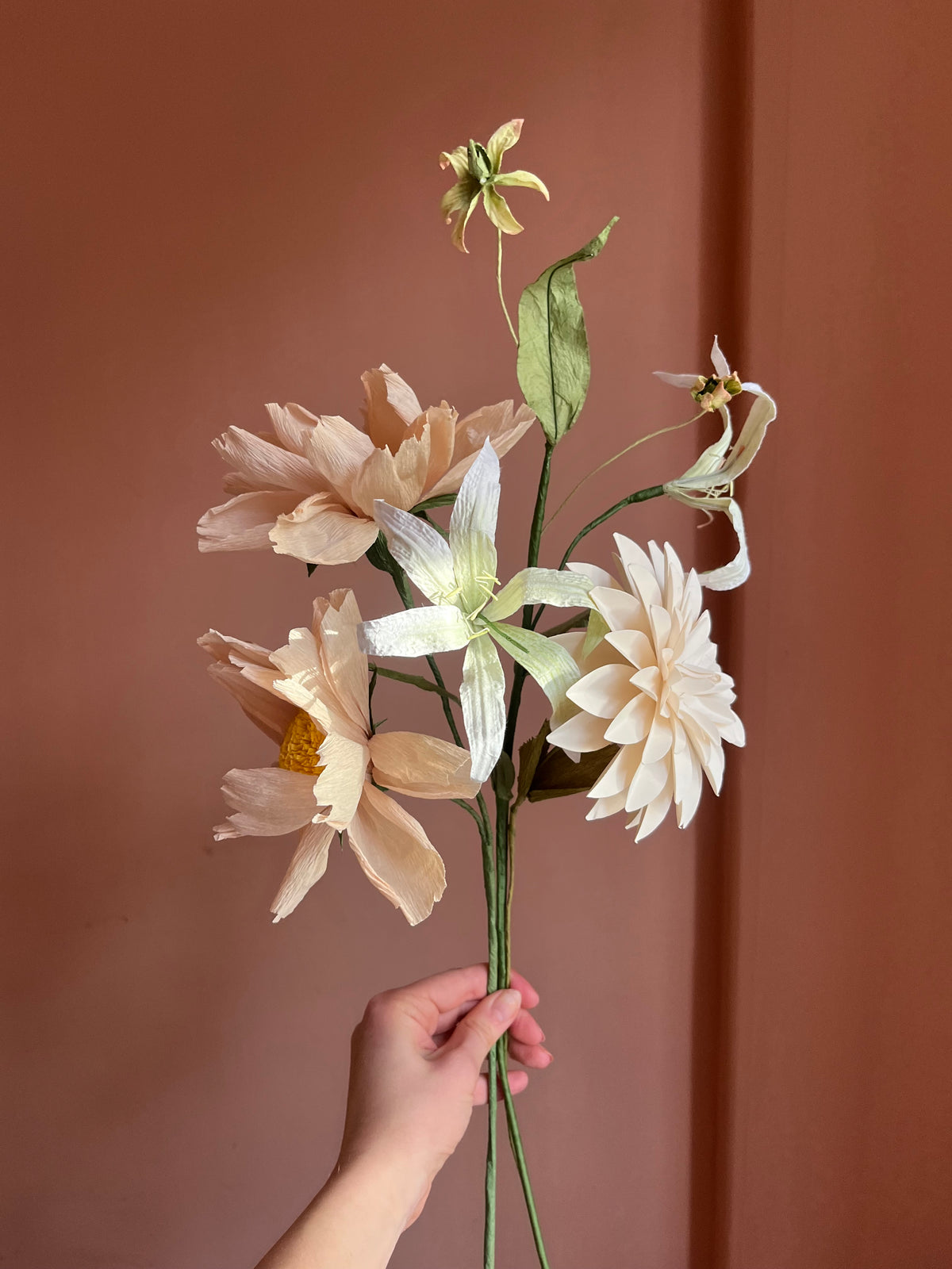 Luftig evighedsbuket af papir i fersken og creme med dahlia og lilje mod rosa væg